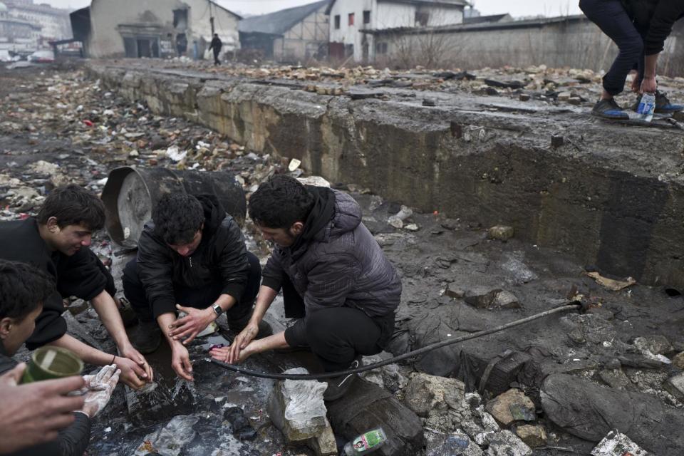 Afghan refugees wash themselves outside an abandoned warehouse where they and other migrants have taken refuge in Belgrade, Serbia, Wednesday, Feb. 1, 2017. Hundreds of migrants have been sleeping rough in freezing conditions in central Belgrade looking for ways to cross the heavily guarded EU borders. (AP Photo/Muhammed Muheisen)