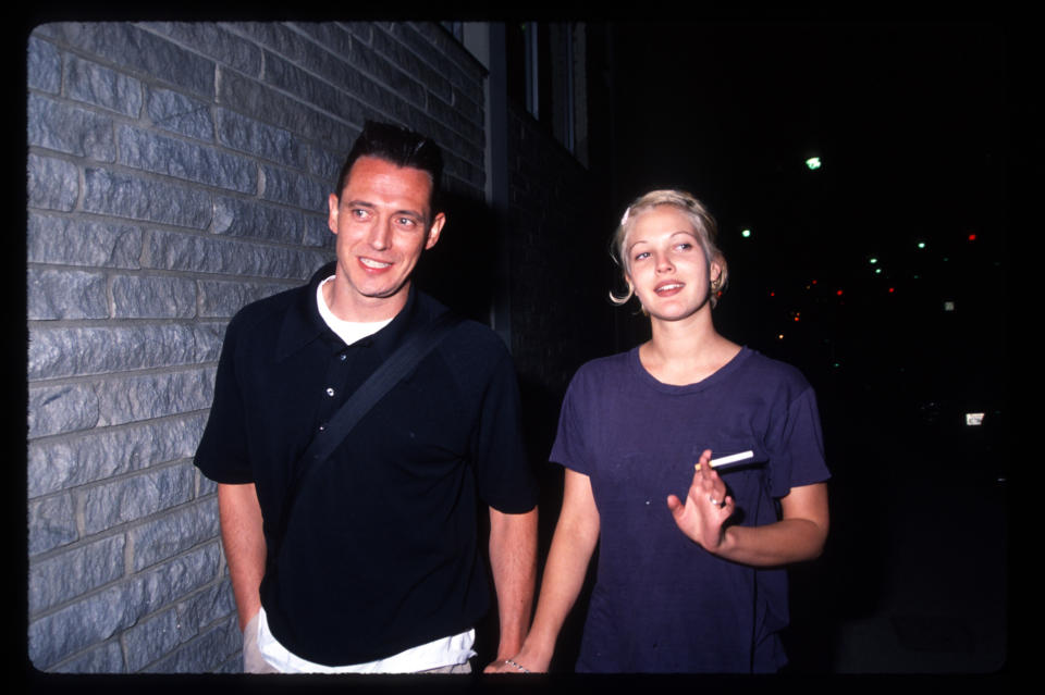 Two people smiling at the camera, one wearing a black shirt and the other wearing a purple top