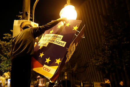 A man puts up a poster reading "To strengthen Europe means to strengthen Germany" after Christian Democratic Union CDU party leader and German Chancellor Angela Merkel wins the German general election (Bundestagswahl), , in Berlin, Germany, September 24, 2017. REUTERS/Axel Schmidt