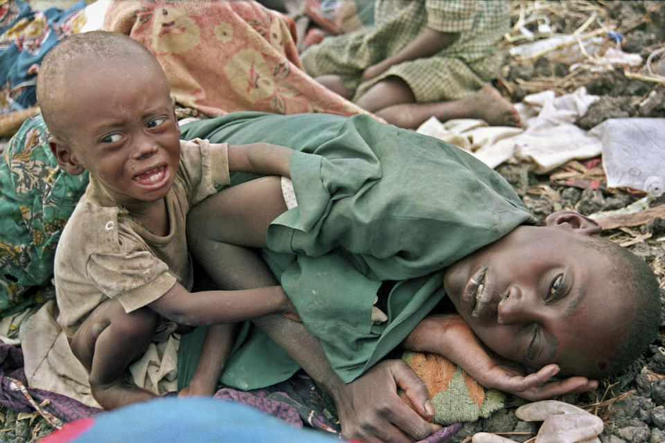 FILE - A Rwandan Hutu refugee child desperately tries to waken his mother from a diseased sleep in the Munigi camp outside Goma, in Zaire, now known as Congo, July 27, 1994. (AP Photo/Javier Bauluz, File)