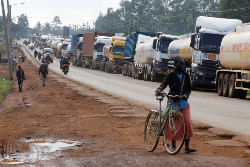 Woman walks past trucks waiting in a 10km queue, to cross Kenyan-Ugandan border in Busia