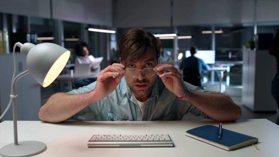 Person leaning over desk and looking over the tops of their glasses. 