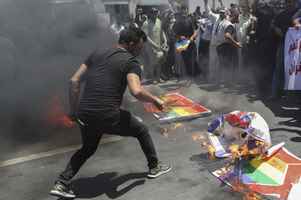 Supporters of Shiite Muslim leader Moqtada Sadr burn a rainbow flag, in response to the burning of a copy of the Quran in Sweden, during open-air Friday prayers in Basra, Iraq, Friday, June 30, 2023. (AP Photo/ Nabil al-Jurani)