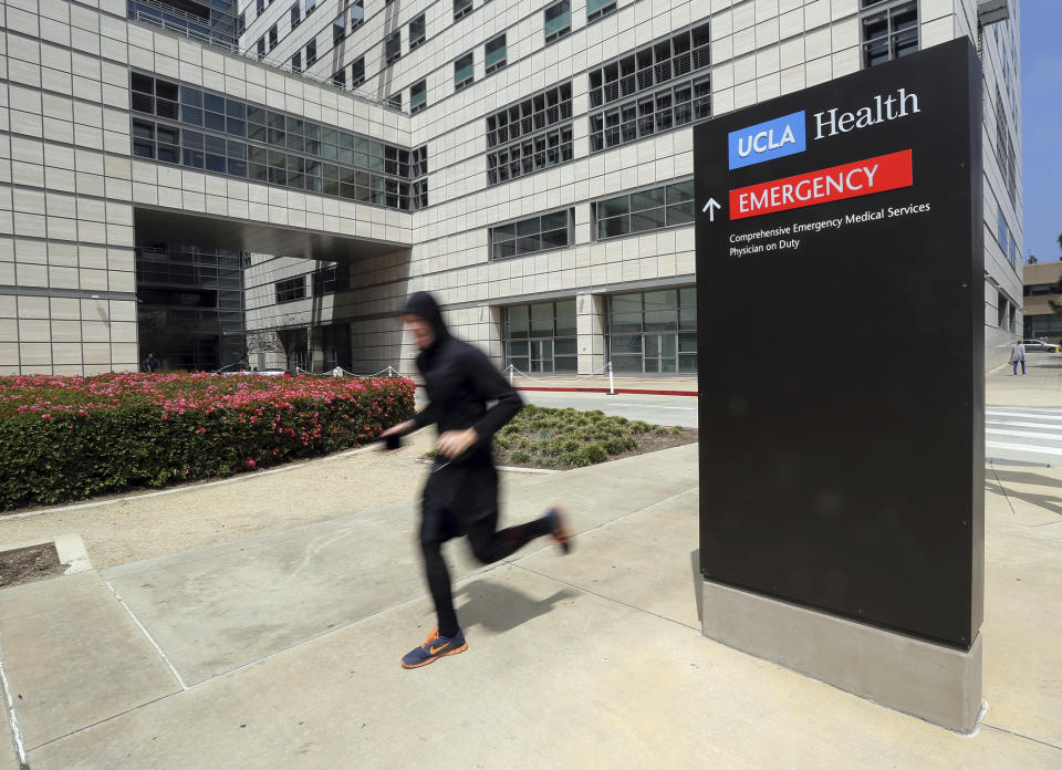 A runner passes the Ronald Reagan UCLA Medical Center on the campus of the University of California, Los Angeles Friday, April 26, 2019. Some students and employees possibly exposed to measles at two Los Angeles universities were still quarantined on campus or told to stay home Friday, but the numbers were dwindling as people were able to show they were vaccinated for the highly contagious disease. The measures were ordered this week at UCLA and California State University, Los Angeles. (AP Photo/Reed Saxon)