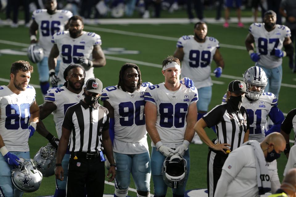 Dallas Cowboys players, Blake Bell (80), DeMarcus Lawrence (90), Dalton Schultz (86), Ezekiel Elliott (21) and others look on as quarterback Dak Prescott, not shown, receives medical attention after suffering a lower right leg injury running the ball against the New York Giants in the second half of an NFL football game in Arlington, Texas, Sunday, Oct. 11, 2020. (AP Photo/Michael Ainsworth)