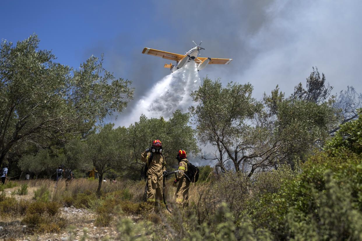 An aircraft drops water as firefighters operate during a wildfire in Vati village, on the Aegean Sea island of Rhodes, southeastern Greece, on Tuesday, July 25, 2023. A third successive heat wave in Greece pushed temperatures back above 40 degrees Celsius (104 degrees Fahrenheit) across parts of the country Tuesday following more nighttime evacuations from fires that have raged out of control for days. (AP Photo/Petros Giannakouris)