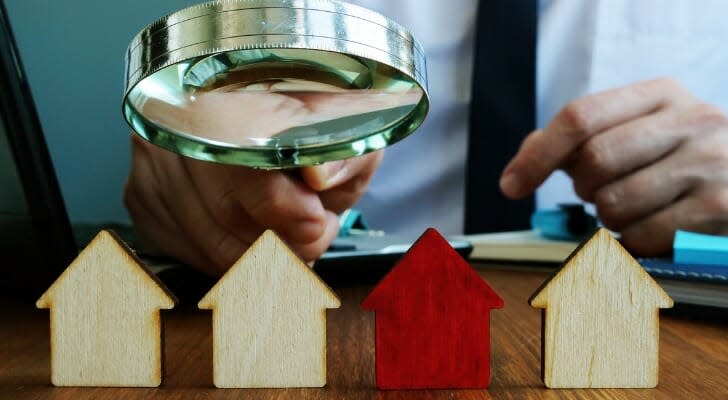 Man looking at toy houses with a magnifying glass