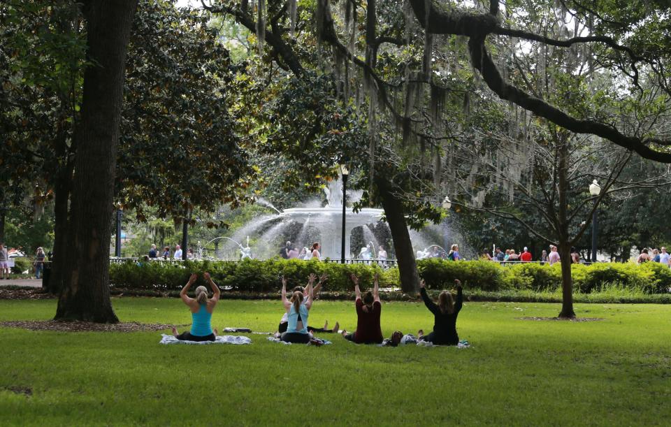Women participate in a yoga class under the oaks in Forsyth Park.