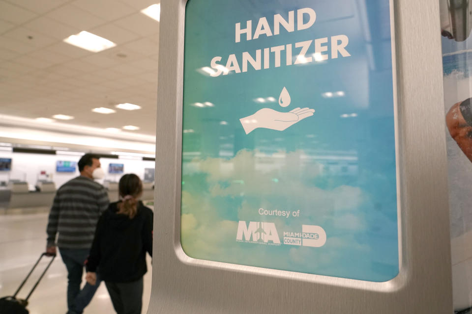 A hand sanitizer dispenser hangs in a concourse at Miami International Airport, Wednesday, Nov. 25, 2020, in Miami. (AP Photo/Lynne Sladky)