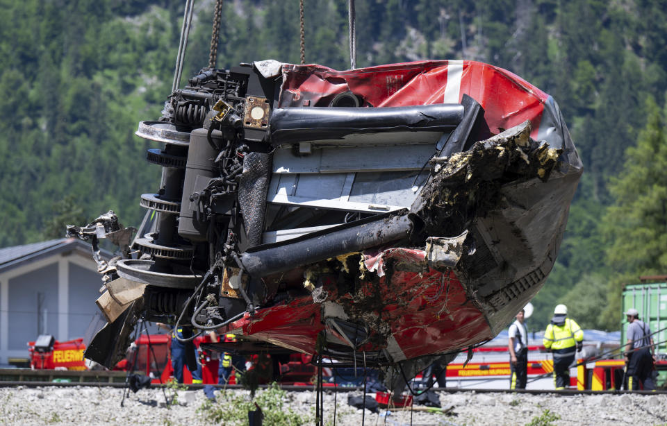 A carriage is being lifted on the site of a train crash in Burgrain, near Garmisch-Partenkirchen, Germany, Saturday, June 4, 2022. Authorities say a train accident in the Alps in southern Germany on Friday left at least four people dead and many more injured. Police said the regional train headed for Munich appears to have derailed shortly after noon in Burgrain — just outside the resort town of Garmisch-Partenkirchen, from where it had set off. Three of the double-deck carriages overturned at least partly, and people were pulled out of the windows to safety. (Sven Hoppe/dpa via AP)