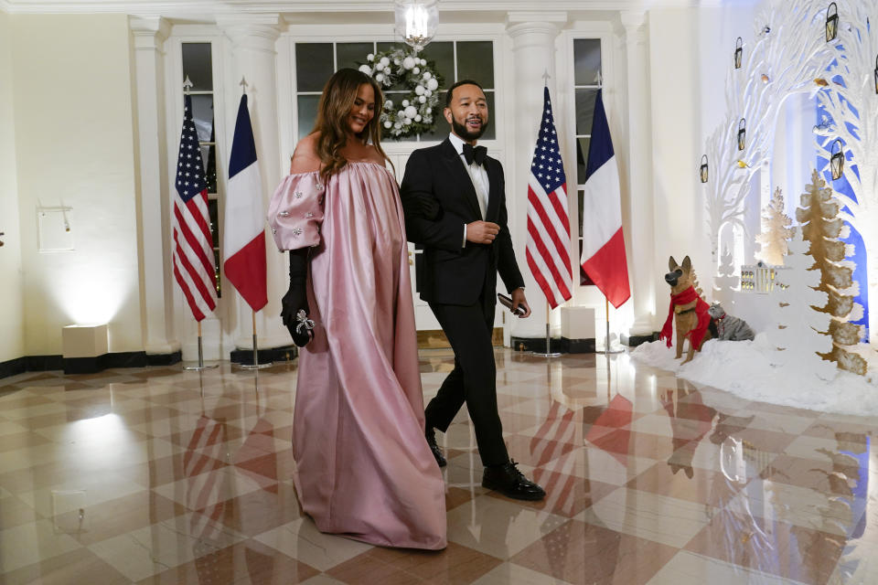 Chrissy Teigen and John Legend, walking past American and French flags, arrive at the White House for the state dinner.