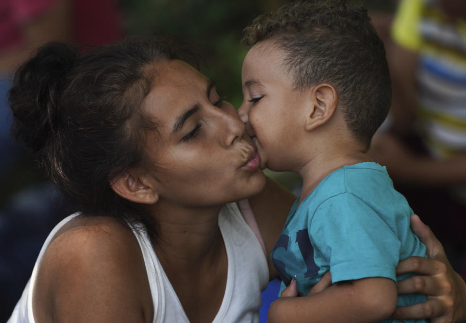 Migrants Alex Pineda kisses his mother Paola Cruz as they rest on the outskirts of Villa Comaltitlan, Chiapas state, Mexico, Wednesday, Oct. 27, 2021. They are part of a migrant caravan headed to the U.S border. (AP Photo/Marco Ugarte)