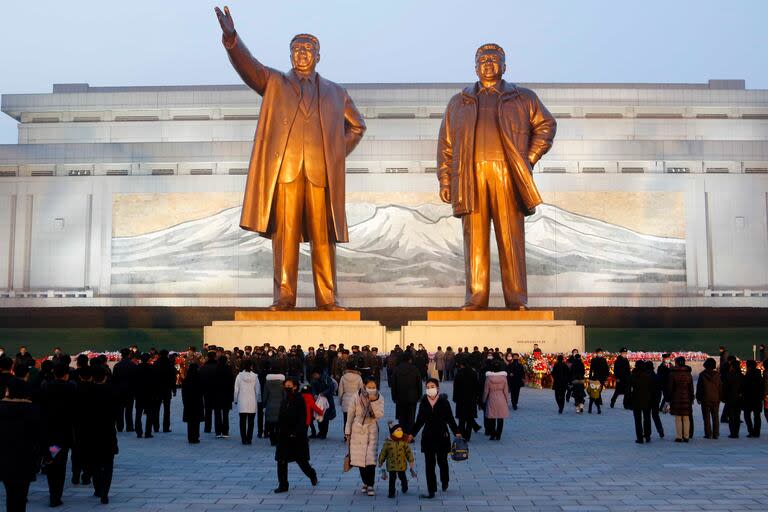 Ciudadanos norcoreanos visitan as estatuas de bronce de sus fallecidos líderes Kim Il-sung (izquierda) y Kim Jong-il, en el monte Mansu, en Pyongyang, Corea del Norte, el 16 de diciembre de 2021, con motivo del décimos aniversario del deceso de Kim Jong-il