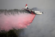 In this Jan. 10, 2020, photo, Rural Fire Service large air tanker 134, operated by Coulson Aviation in the U.S. state of Oregon, drops fire retardant on a wildfire burning close to homes at Penrose, Australia, 165km south of Sydney. Three American crew members died Thursday when this C-130 Hercules aerial water tanker crashed while battling wildfires in southeastern Australia, officials said. (Dan Himbrechts/AAP Image via AP)