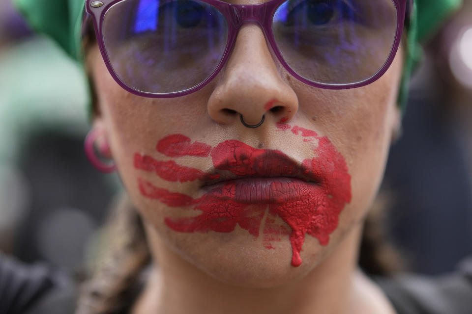 Una mujer en el Día Internacional de la Mujer con una mano roja pintada en la cara, simbolizando la desaparición y muerte de mujeres indígenas, en Bogotá, Colombia, el viernes 8 de marzo de 2024. (AP Foto/Fernando Vergara)