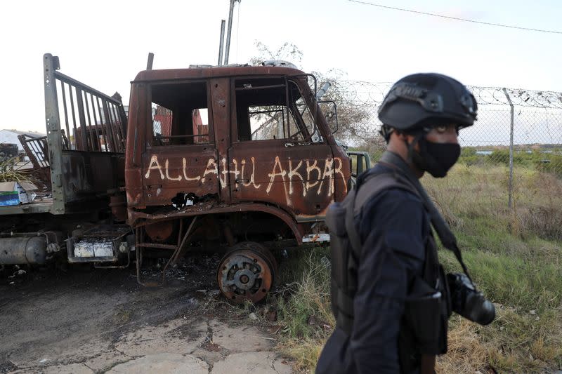 Rwandan security forces police officer walks past a burned truck at the port of Mocimboa da Praia