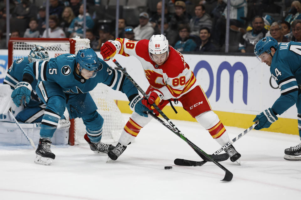 San Jose Sharks defenseman Matt Benning (5) and defenseman Marc-Edouard Vlasic (44) battle for the puck against Calgary Flames left wing Andrew Mangiapane (88) in the second period of an NHL hockey game Sunday, Dec. 18, 2022, in San Jose, Calif. (AP Photo/Josie Lepe)
