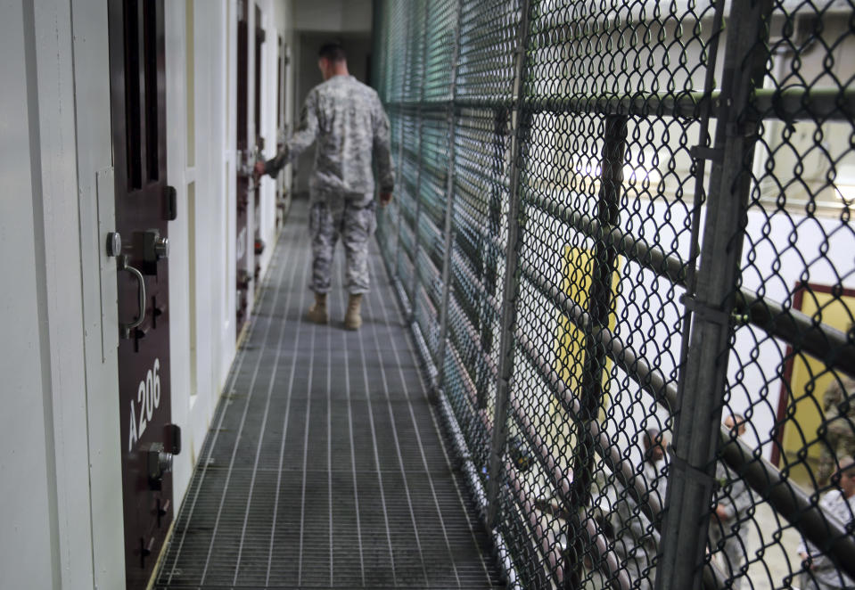 FILE - In this Feb. 6, 2016, file photo, an Army captain walks outside unoccupied detainee cells inside Camp 6 at the U.S. detention center at Guantanamo Bay, Cuba. The 20th anniversary of the first prisoners' arrival at the Guantanamo Bay detention center is on Tuesday, Jan. 11, 2022. There are now 39 prisoners left. At its peak, in 2003, the detention center held nearly 680 prisoners. (AP Photo/Ben Fox, File)
