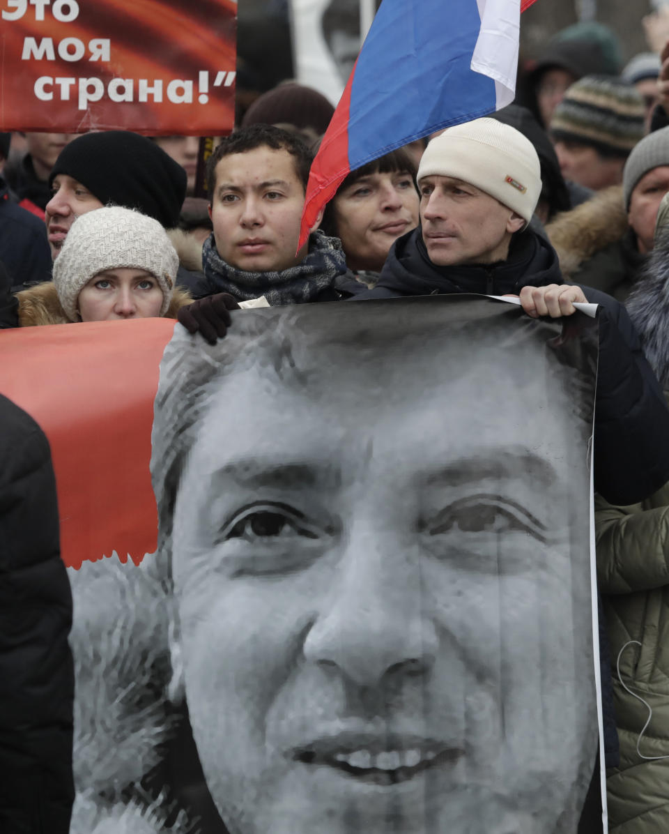 Demonstrators carry a banner with a portrait of Boris Nemtsov march in memory of opposition leader Boris Nemtsov in Moscow, Russia, Sunday, Feb. 24, 2019. Thousands of Russians took to the streets of downtown Moscow to mark four years since Nemtsov was gunned down outside the Kremlin. (AP Photo/Pavel Golovkin)