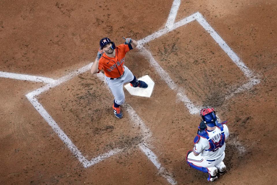 Houston Astros' Jose Altuve, left, celebrates after hitting a home run as Texas Rangers catcher Jonah Heim kneels behind home plate during the third inning in Game 3 of the baseball American League Championship Series Wednesday, Oct. 18, 2023, in Arlington, Texas.