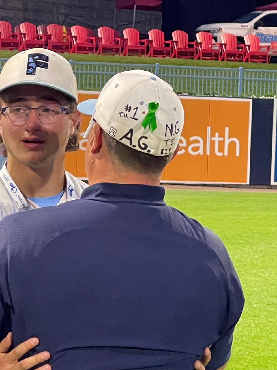 Franklin baseball coach Zach Brown hugged each one of his players after the Panthers fell to Taunton in Sunday's state championship game. His hat is covered with the initials of Anthony Gates and Nick Gaspar, who both died during the season.