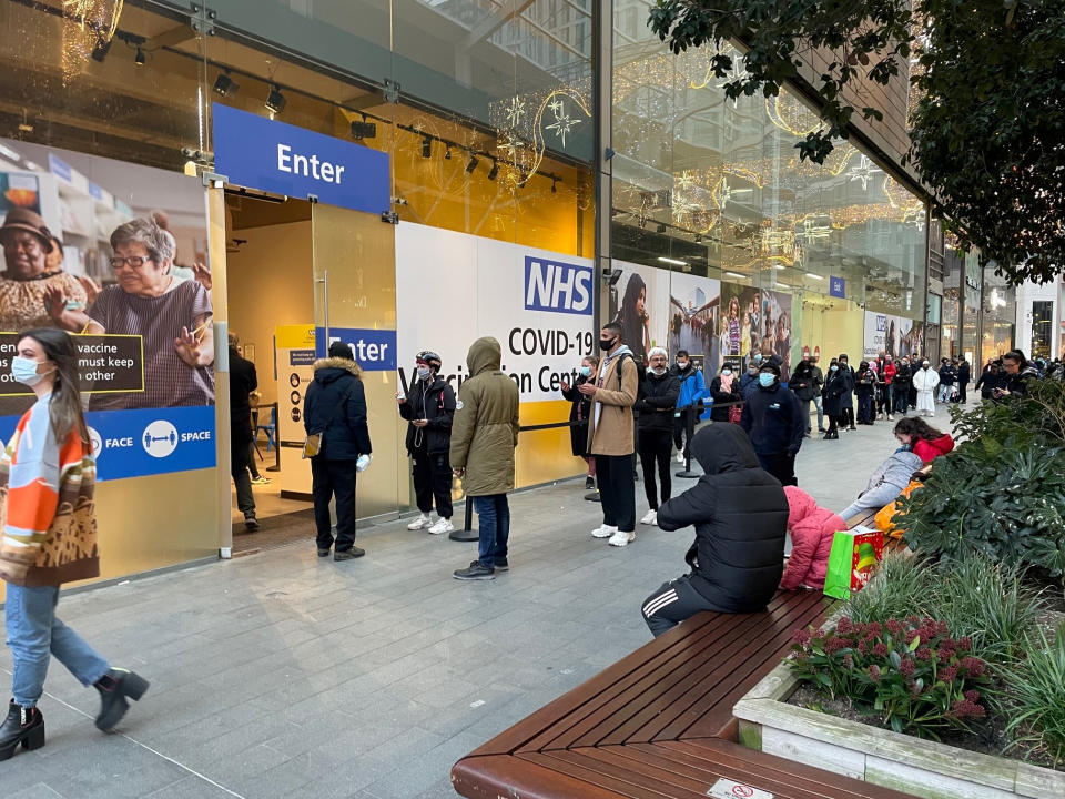 People queue at a COVID Vaccination Centre at the Westfield shopping centre in Stratford, east London, as the coronavirus booster vaccination programme continues across the UK. Despite the ramping-up of the booster programme, experts said it would not help in terms of hospitals admissions in the near future, as many would be people who are infected now before immunity has had time to build. Picture date: Monday December 20, 2021. (Photo by Jonathan Brady/PA Images via Getty Images)