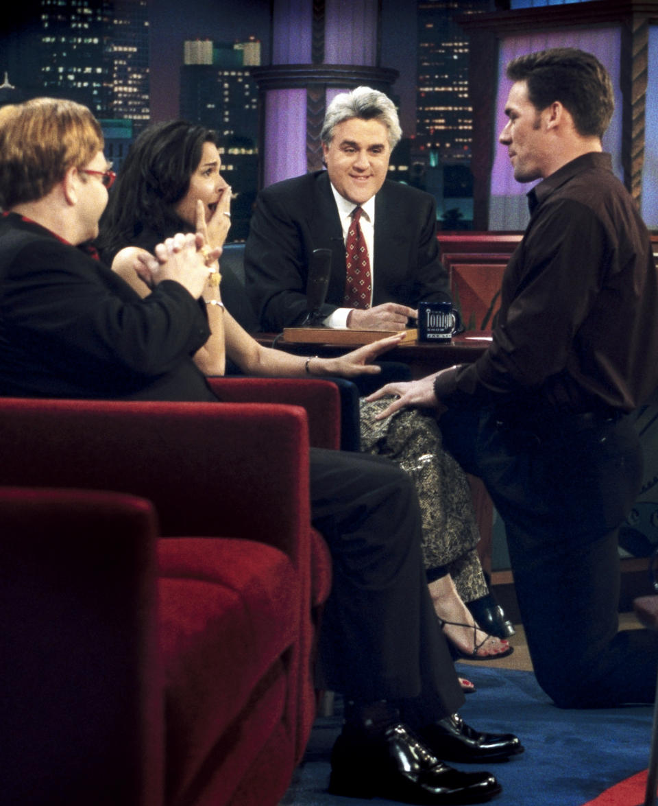 This March 13, 2000 photo released by NBC shows Elton John, left, and host Jay Leno, center, looking on as professional football player Jason Sehorn, right, proposes to actress Angie Harmon on "The Tonight Show with Jay Leno," in Burbank, Calif. After 22 years, Leno will host his last show on Thursday, Feb. 6, 2014. (AP Photo/NBC, Paul Drinkwater)