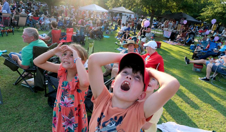 Music lovers gather at Government Plaza for Live at the Plaza Friday, June 23, 2023. Jooniper Smith, Cole Stevens, and his brother Grant Stevens (partially obscured) look up in wonder at a pair of balloons that are floating away. 