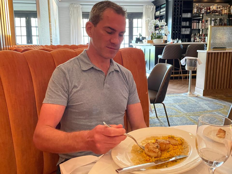 Steven getting ready to take a bite of a scallop dish at a chain restaurant