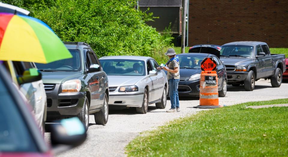 Carrie Scott welcomes people and places a sticky note on their car to signal the amount of food they will receive at Pantry 279 on Wednesday, June 15, 2022.