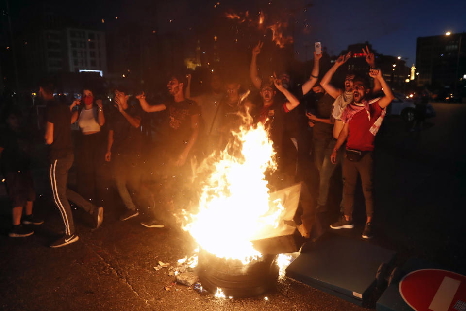 Anti-government protesters chant slogans as they burn barriers to block a road during a protest against the political leadership they blame for the economic and financial crisis, in front of the government house in downtown Beirut, Lebanon, Thursday, June 11, 2020. (AP Photo / Hussein Malla)