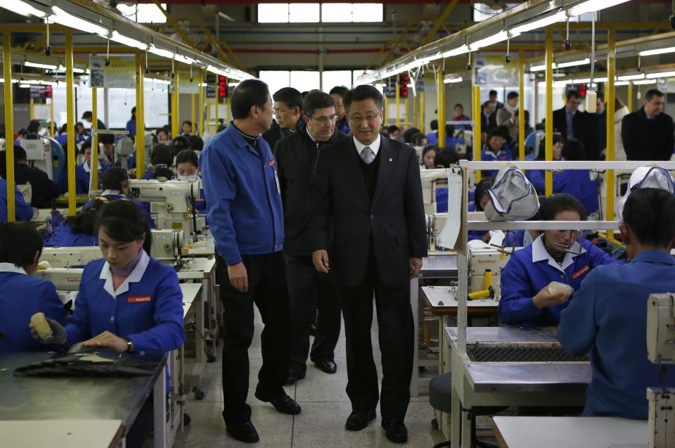 Hong Yang-ho (R), chairman of the Kaesong Industrial District Management Committee, takes a tour in a factory of a South Korean company with officials from the G20 Seoul Conference at the Joint Industrial Park in Kaesong, a few miles inside North Korea from the heavily fortified border December 19, 2013. North Korea hosted a group of foreign officials and journalists on Thursday in a rare opening of the industrial zone jointly run with the South, a week after the regime executed the powerful uncle of leader Kim Jong Un. North and South Korean officials also held meetings at the Kaesong complex on Thursday to discuss the operations of the factory park, their first contact since the purge of Jang Song Thaek, considered the second-most powerful man in the country. REUTERS/Kim Hong-Ji (NORTH KOREA - Tags: BUSINESS EMPLOYMENT POLITICS)