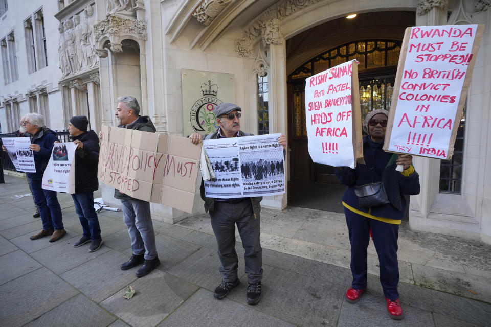 Protesters stand outside the Supreme Court in London, Wednesday, Nov. 15, 2023. Britain's highest court is set to rule Wednesday, Nov. 15 on whether the government's plan to send asylum-seekers to Rwanda is legal, delivering a boost or a blow to a contentious central policy of Prime Minister Rishi Sunak's administration. Five justices on the U.K. Supreme Court will deliver judgment in the government's attempt to overturn a lower court ruling that blocked deportations. (AP Photo/Kirsty Wigglesworth)