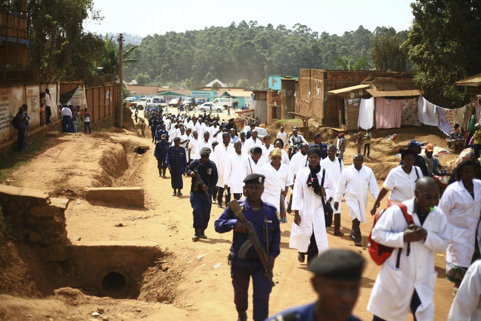 Doctors and health workers march in the Eastern Congo town of Butembo on Wednesday April 24, 2019, after attackers last week shot and killed an epidemiologist from Cameroon who was working for the World Health Organization. Doctors at the epicenter of Congo's Ebola's crisis are threatening to go on strike indefinitely if health workers are attacked again. (AP Photo/Al-hadji Kudra Maliro)