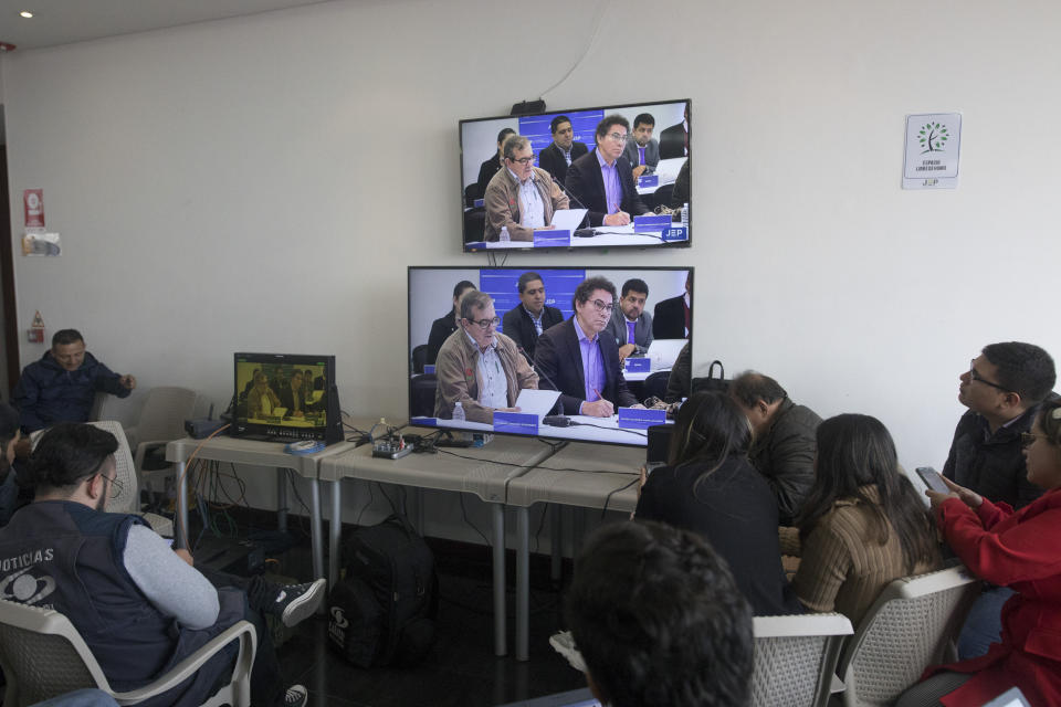 Journalists watch former rebel leaders' appearance before Colombia's special peace tribunal to testify in an ongoing probe of their role in civilian kidnappings in Bogota, Colombia, Monday, Sept. 23, 2019. (AP Photo/Ivan Valencia)