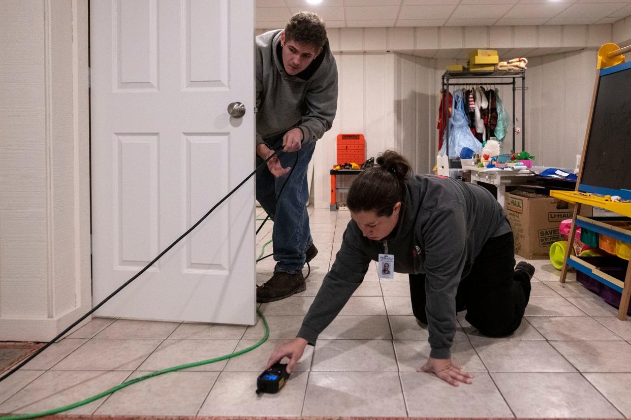 Menold employee Christopher Angeli unplugs equipment while co-worker Angie Semon reads the moisture levels of a home in Washington on Nov. 22, 2021.
