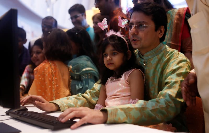 A stockbroker and his daughter watch a terminal during a special "muhurat" trading session for Diwali, the Hindu festival of lights, at the Bombay Stock Exchange (BSE) in Mumbai
