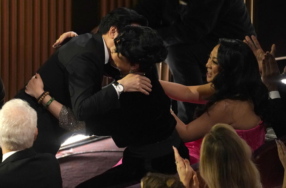 Ke Huy Quan, from left, is hugged in the audience by Echo Quan as he accepts the award for best performance by an actor in a supporting role for "Everything Everywhere All at Once" at the Oscars on Sunday, March 12, 2023, at the Dolby Theatre in Los Angeles. Stephanie Hsu looks on from right. (AP Photo/Chris Pizzello)