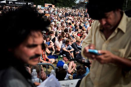 Revellers listen to American whistleblower Edward Snowden (unseen) as he is interviewed by the performance group The Yes Men (front) during the Roskilde Festival in Roskilde, Denmark, June 28 2016. Scanpix Denmark/Mathias Loevgreen Bojesen /via REUTERS