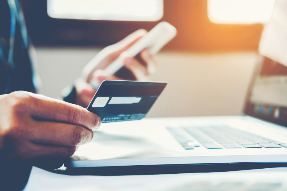 Person holding credit card sitting in front of computer.