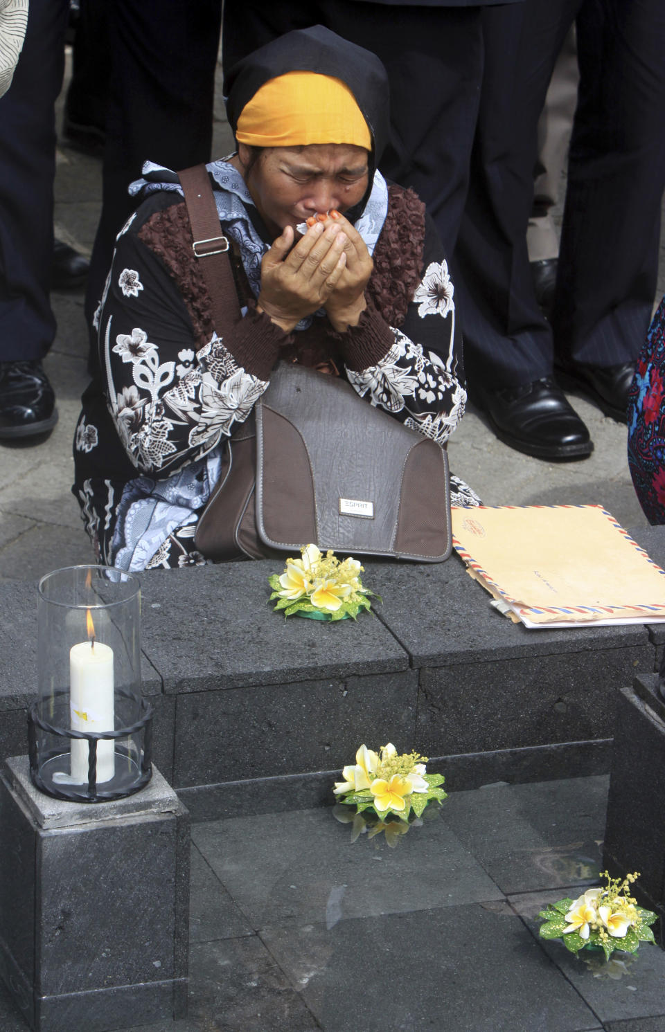 An Indonesian woman grieves for victims of the 2002 Bali bombings at a memorial pond during a memorial service to mark the 10th anniversary of the terrorists attacks in Kuta, in Jimbaran in Bali, Indonesia, Friday, Oct. 12, 2012. A decade after twin bombs killed scores of tourists partying at two beachfront nightclubs on Indonesia's resort island of Bali, survivors and victims' families on Friday braved a fresh terrorism threat to remember those lost to the tragedy. (AP Photo/Firdia Lisnawati)