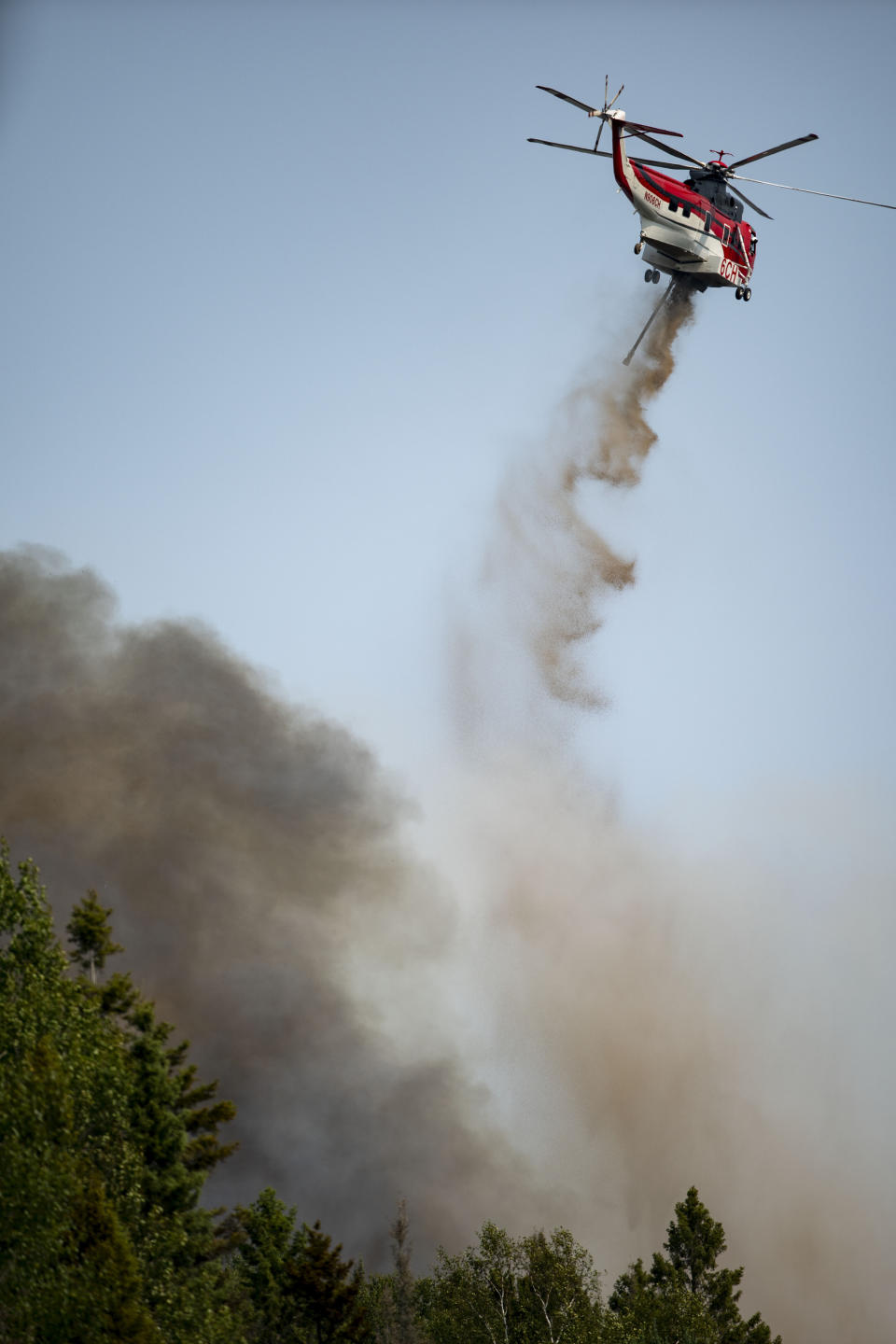 A helicopter drops fire retardant on a portion of the Greenwood Fire near Highway 2 as it moves northeast on Monday, Aug. 16, 2021, in Duluth, Minn. The wildfire has continued to grow and spread towards the northeast as firefighters battle the flames from both the ground and air. (Alex Kormann/Star Tribune via AP)