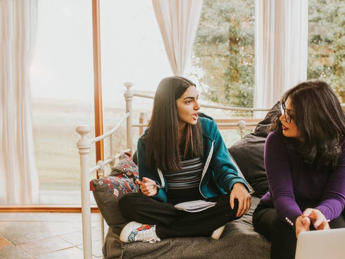 mom sits next to her teen daughter talking on a daybed