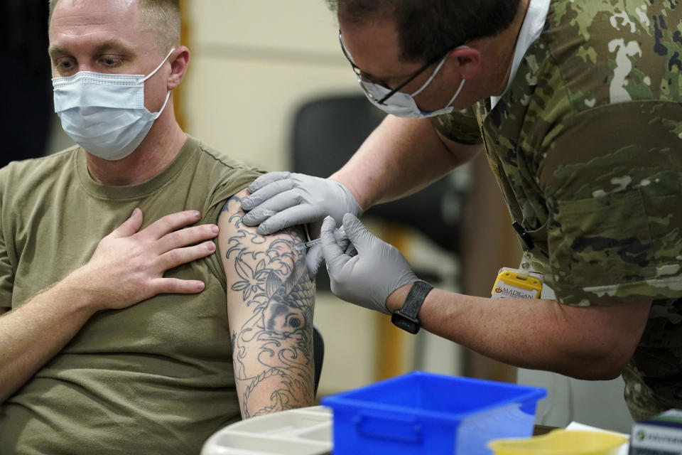 FILE - Staff Sgt. Travis Snyder, left, receives the first dose of the Pfizer COVID-19 vaccine given at Madigan Army Medical Center at Joint Base Lewis-McChord in Washington state, Dec. 16, 2020, south of Seattle. A bill to rescind the COVID-19 vaccine mandate for members of the U.S. military has passed the House. The bill approved Thursday directs Defense Secretary Lloyd Austin to rescind his 2021 order requiring COVID vaccination. (AP Photo/Ted S. Warren, File)