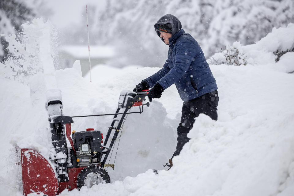 Kelly Orth works his way out of waist deep snow in front of his home in Apple Valley, Minn., on Wednesday, Jan. 4, 2023. (Elizabeth Flores/Star Tribune via AP)