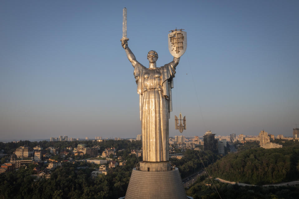 Workers install the Ukrainian coat of arms on the shield in the hand of the country's tallest stature, the Motherland Monument, after the Soviet coat of arms was removed, in Kyiv, Ukraine, Sunday, Aug. 6, 2023. Ukraine is accelerating efforts to erase the vestiges of centuries of Soviet and Russian influence from the public space amid the Russian invasion of Ukraine by pulling down monuments and renaming hundreds of streets to honor home-grown artists, poets, military chiefs, and independence leaders. (AP Photo/Efrem Lukatsky)