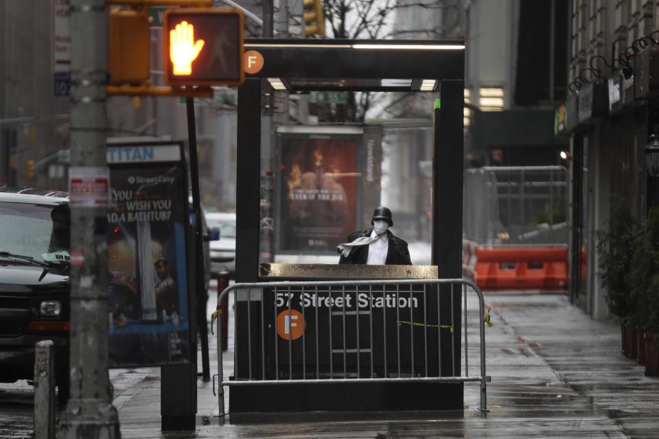 FILE - In this April 13, 2020 file photo, a man enters the subway on a rainy day in New York. New York City transit officials said they're providing buses for homeless people to shelter from unseasonably frigid temperatures this weekend during newly instituted overnight subway closures. The subway system has been shutting down from 1 to 5 a.m. since Wednesday, May 6, as part of an outbreak-related plan for daily train disinfecting. (AP Photo/Seth Wenig, File)