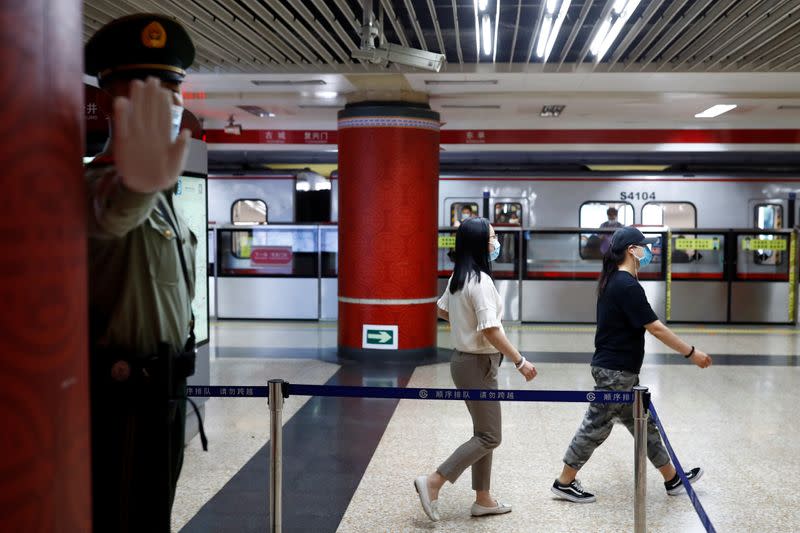 A Paramilitary police officers gestures at the photographer while keeping watch at a station of Line 1 of the metro that runs past the Great Hall of the People