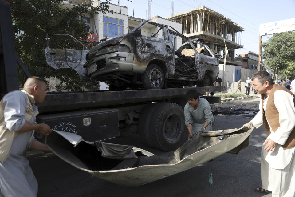 Security personnel remove a damaged minivan after a bomb explosion in Kabul, Afghanistan, Saturday, June 12, 2021. Separate bombs hit two minivans in a mostly Shiite neighborhood in the Afghan capital Saturday, killing several people and wounding others, the Interior Ministry said. (AP Photo/Rahmat Gul)