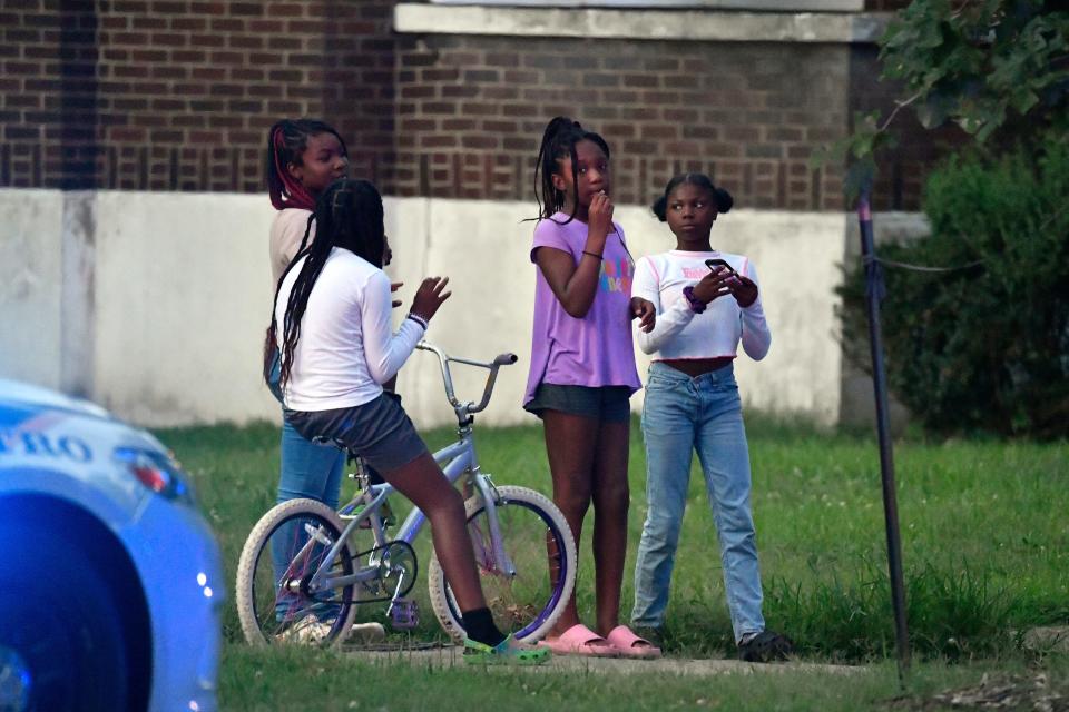 Neighborhood kids look on as Louisville Police search the scene of a shooting at the baseball fields in Shawnee Park, Sunday, July 10 2022 in Louisville Ky.